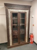 An Eastern carved hardwood glazed double door cabinet fitted with two drawers ,
