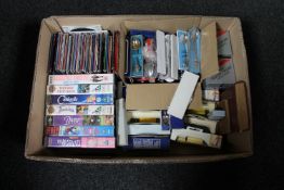 A box containing VHS cassette tapes, crested teaspoons,
