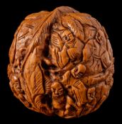 A Japanese carved walnut: the exterior decorated with figures in a garden landscape, 4cm. high.