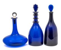 Three blue glass decanters: comprising a mallet shaped example with triple neck rim and faceted