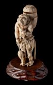 A Japanese carved ivory okimono of an Oni, unsigned: with straw basket on his back holding a fish,