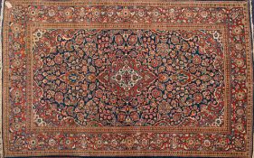 A Kashan rug:, the indigo cartouche field with a central rust shaped lozenge pole medallion,