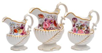A graduated set of three early 19th century English porcelain jugs: of nautilus shell moulded form