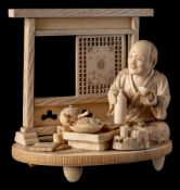 A Japanese carved ivory okimono of a man enjoying a small feast,