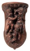 A carved wooden wall bracket: in the Italianate taste decorated with three cherubs within a foliate