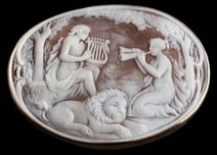 A large oval shell cameo brooch: depicting two maidens serenading a recumbent lion within a plain