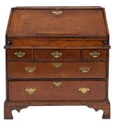 An early 18th Century oak bureau:, the sloping hinged fall fitted with a ledge,
