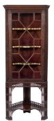An Edwardian carved mahogany corner display cabinet on a stand:, with canted angles,