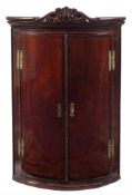 A mid 18th Century mahogany bow-fronted hanging corner cupboard:,