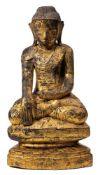 A carved wood and parcel gilt figure of Buddha: seated crossed legged on a lotus flower wearing