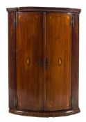 A mid 18th Century mahogany and inlaid bow-fronted hanging corner cupboard:, with a moulded cornice,