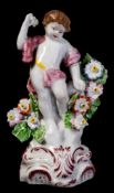 A Plymouth figure of a putto: with bocage support and holding a flower aloft,
