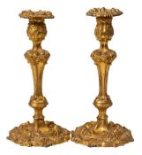A pair of 19th century gilded copper candlesticks: with acanthus decorated nozzles on a knopped and