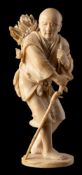 A Japanese carved ivory okimono of a peasant farmer carrying a bundle of wood on his back,