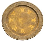 An Islamic brass dish: engraved overall with intricate geometrical decoration and panels of text,