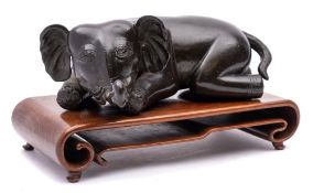 A Chinese bronze model of a recumbant elephant: with trunk outstretched, 25cm long,