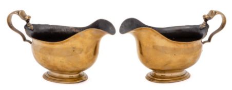 A pair of 18th Century brass sauceboats: of traditional design with scroll handles mounted on oval