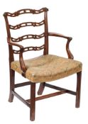 A George III carved mahogany ladderback elbow chair: the shaped and pierced splats with scroll