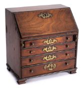 A George III period miniature mahogany writing bureau: the sloping hinged fall enclosing an