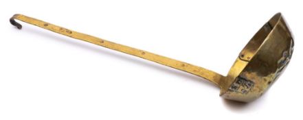 A very large 18th Century brass ladle: the bowl well patched and the flat handle crooked at the top,