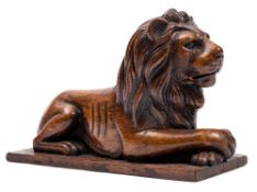 An early 19th Century carved padouk wood model of a recumbent lion: with crossed front paws on a