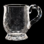A small clear glass mug: of thistle shaped form with facet cut handle and slice cut rim and foot,