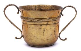 A late 17th/early 18th Century brass porringer: with two cast and beaded scroll handles to the