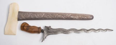A Malay kris:, the shaped damascus blade over a gem set hilt and shaped wooden grip,