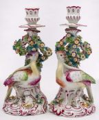 A pair of Continental exotic bird candlesticks in the Chelsea style: on rococo mound bases with