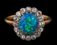A black opal and diamond oval cluster ring: the central oval black opal approximately 10mm long x 8.