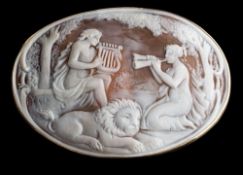 A large oval shell cameo brooch: depicting two maidens serenading a recumbent lion within a plain