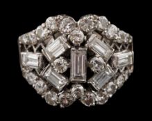 A diamond mounted cocktail cluster ring: with a symmetrical cluster of brilliant and baguette-cut
