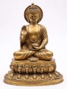 A large gilt brass figure of Buddha: seated crossed legged in traditional robes, on a lotus flower,