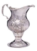 A George III silver embossed pedestal cream jug, maker's mark worn, London,