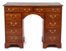 A mahogany rectangular kneehole desk:, the top inset with a panel of tooled leather,