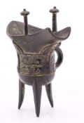 A small Chinese 'archaic' bronze wine vessel [Jue]: of conventional form cast with taotie masks on