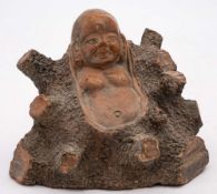 A Chinese Yixing figure of Budai: emerging from a large tree stump, 11cm. high [minor losses].