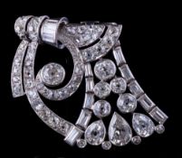 A platinum and diamond clip brooch: of openwork scroll design with round and pear-shaped old