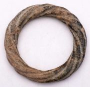 A Chinese calcified jade bangle: of archaic form, carved as a continuous twisted rope, 11cm.