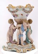 A Meissen porcelain group: modelled with three scantily clad putti supporting a large footed vase