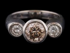 A diamond three-stone ring: with central light brown diamond approximately 6.8mm diameter x 4.
