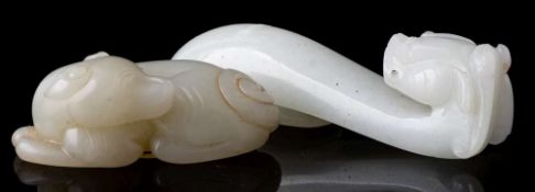 A Chinese celadon jade carving of a dog and a dragon belt hook: the dog recumbent with its head