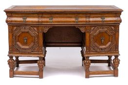 A similar oak kneehole writing desk: of canted design with a tooled leather inset moulded top,