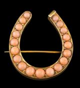 A late 19th Century gold and coral mounted horseshoe brooch: with graduated circular coral,