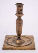 A 17th Century Continental brass candlestick: with plain cylindrical nozzle on a slender tapering