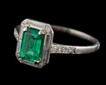 An Art Deco emerald and diamond rectangular cluster ring: with central emerald-cut emerald