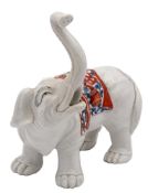 A Chantilly-style porcelain elephant: modelled with trunk raised and wearing a saddle cloth