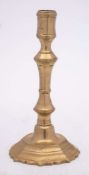 An 18th Century French brass candlestick: the octagonal shaped nozzle on a knopped stem,