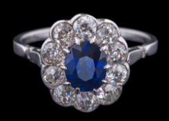 A sapphire and diamond oval cluster ring: the central, oval sapphire approximately 6.4mm long x 5.