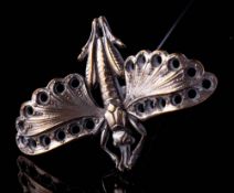 An early 20th century silver plated hat pin in the form of a flying cricket,